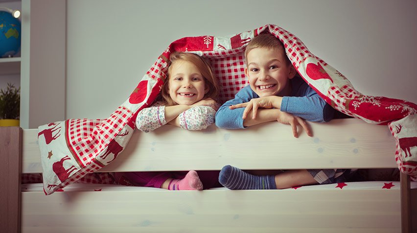 Girl and boy smiling in the top bunk