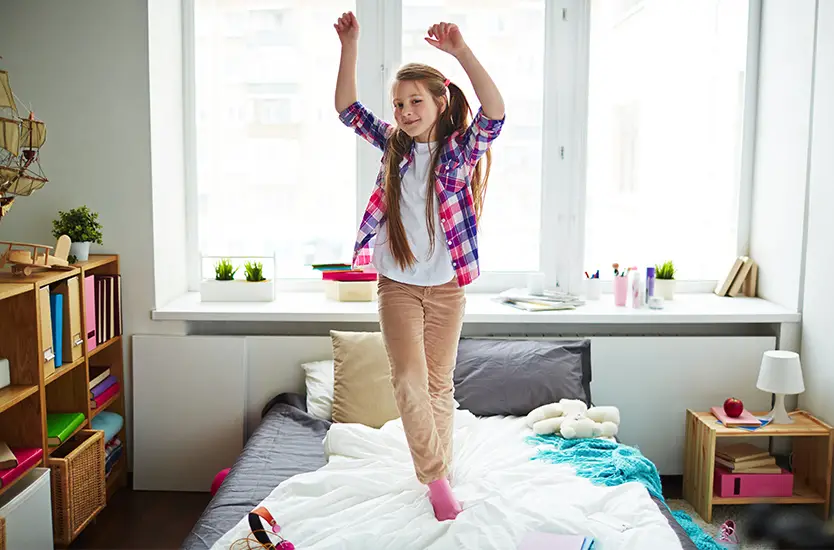 Teenage girl jumping on bed