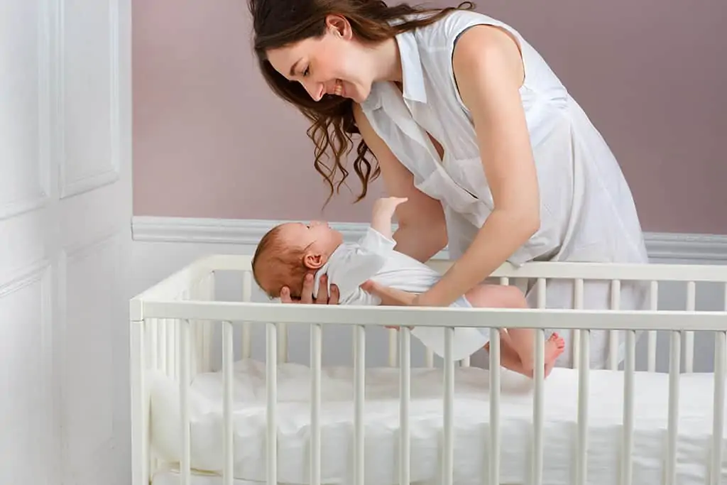 Mother putting baby in crib